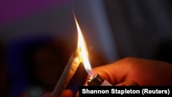 Un bărbat aprinde un joint de canabis. Imagine generică.