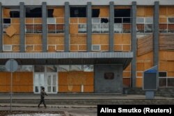 Покровськ потерпає від російських обстрілів, тепер у місто залітають і FPV-дрони армії РФ. На фото: місцевий житель іде повз пошкоджену ударами будівлю Палацу культури, Покровськ, грудень 2024 року