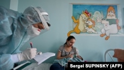 Молода матір тримає кисневу маску на обличчі своєї хворої на Covid-19 дитини. Ковідне відділення дитячої лікарні. Київ, 16 листопада 2021 року. (Фото Сергія СУПИНСЬКОГО/ AFP)