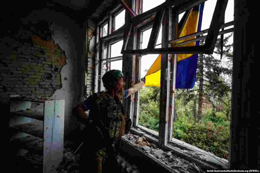 Український військовий із позивним «Борода» з 68-ї окремої єгерської бригади імені Олекси Довбуша розправляє український прапор у звільненому селі Благодатне на Донеччині, червень 2023 року