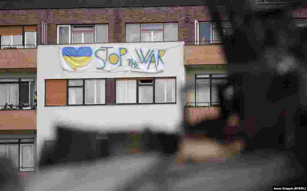 Антивоена парола виси од станбен блок со поглед на руските возила во Прага. Илја Кучински, украински доброволец и член на територијалните одбранбени сили на земјата, кој ја подготвуваше изложбата за нејзиното отворање на 11 јули, за РСЕ изјави дека изложбата била наменета &bdquo;да ги потсети луѓето дека војната не е толку далеку како што мислат. Чешка е една од следните. И бидете сигурни дека [Русија] нема да запре&ldquo;.