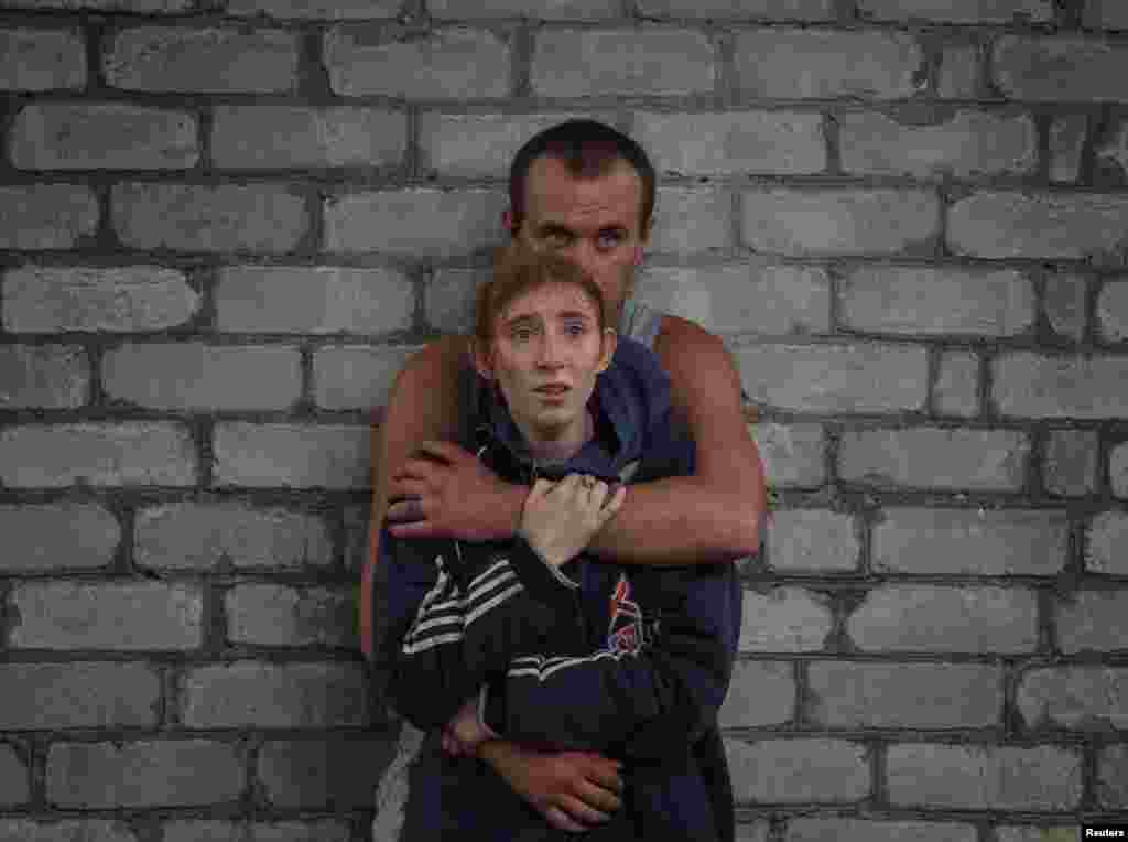 Family members watch rescuers work as they wait for news about their relatives who are under the rubble of a residential building damaged by a Russian military strike in the town of Chasiv Yar, in the Donetsk region, on July 10, 2022.