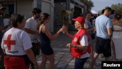 Lucrătorii Crucii Roșii elene împart apă turiștilor la poalele Acropolei, miercuri, 12 iunie. 