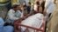 Relatives sit beside the body of a female polio vaccinator who was killed by unidentified gunman in Chaman on April 25.