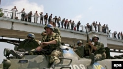 Російські війська проїздять повз грузинських протестувальників в місті Поті на заході Грузії. 23 серпня 2008 року.