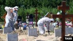 Sankt Petersburg, gropari în echipament de protecție la un cimitir din oraș, îngroapă victime ale pandemiei de Covid-19, Rusia, iulie 2021.