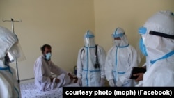 FILE: Healthcare workers treat a person infected with the coronavirus in the eastern Afghan province of Laghman in June.