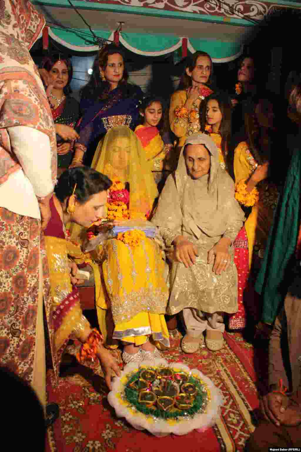 Elderly women apply henna to the bride&#39;s feet. 