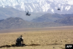 Un soldat american, fotografiat alături de două elicoptere americane Cobra, ce se întorceau de pe câmpul de luptă din Gardez și se pregătesc să aterizeze. Fotografie realizată la data de 13 martie 2002, în timpul operațiunii Anaconda.