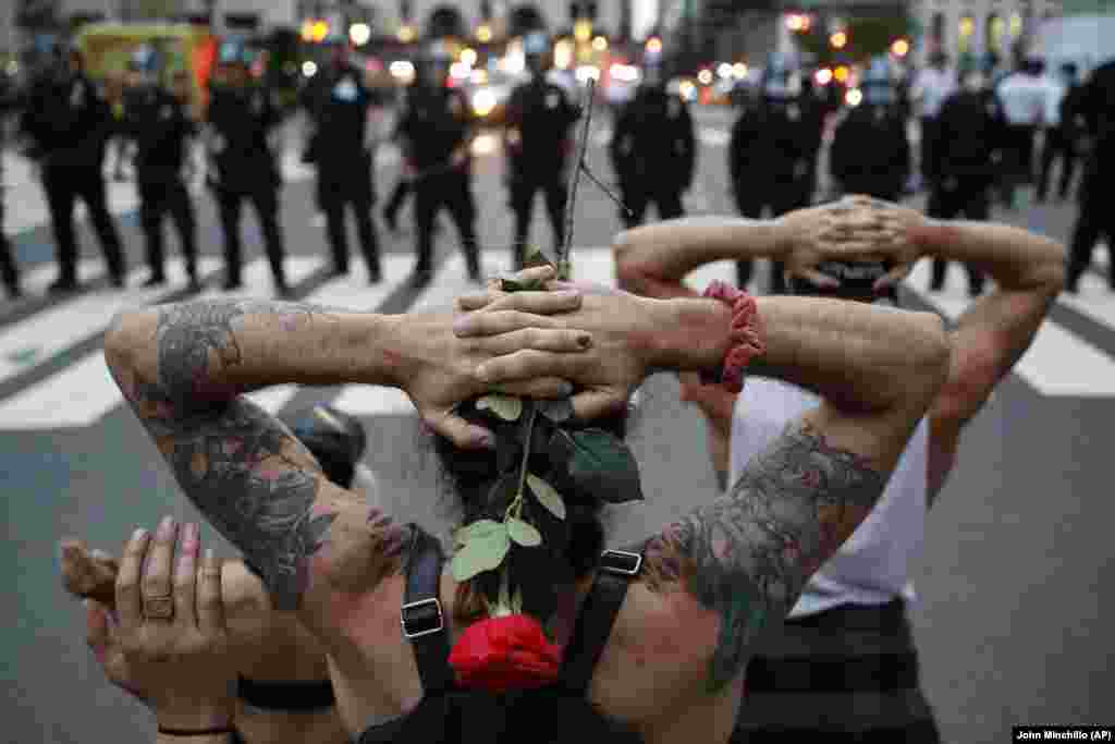 Protesters kneel in front of New York City Police Department officers before being arrested for violating curfew beside the iconic Plaza Hotel on 59th Street, Wednesday, June 3, 2020, in New York.
