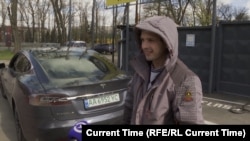 Ukrainian taxi driver Anatoliy Trepak stands next to his recently purchased Tesla in Kyiv.