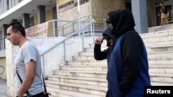 Горан Грујевски и Никола Бошкоски, под придружба на грчки полицаец, го напуштаат судот во Солун