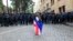 Un manifestant îmbrăcat în steagurile naționale georgiene și ale UE stă în fața unui cordon de poliție în timpul unui protest al opoziției la Tbilisi. 