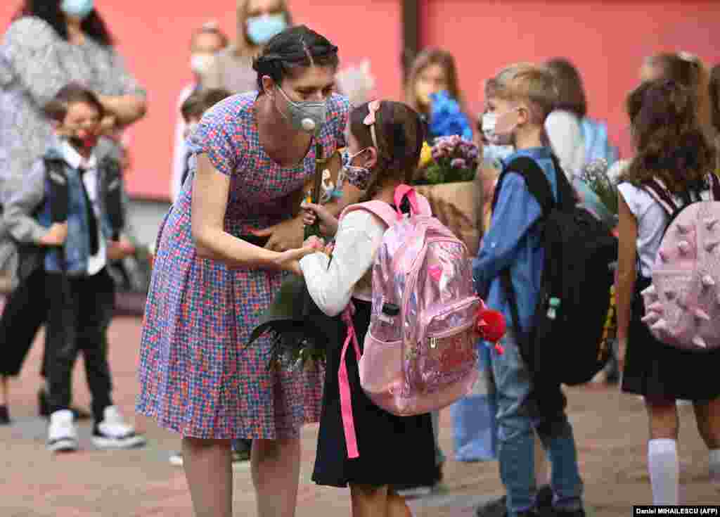 A woman and a girl wearing protective face masks chat as they gather with teachers, parents, and other children in front of a school in the Romanian capital, Bucharest, on September 14 as classes started again after the summer break.&nbsp;​Due to the coronavirus pandemic, most of Romania&#39;s schools reopened with students alternating between classroom learning and remote education.