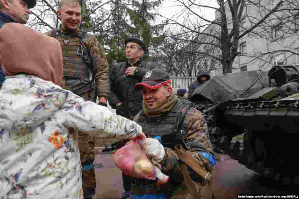 Дзяўчынка дае пакунак зь яблыкамі ўкраінскаму вайскоўцу ў горадзе Бахмач Чарнігаўскай вобласьці. Вызваленьне Чарнігаўшчыны ад расейскіх войскаў. Красавік 2022 году