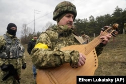 Відомий український артист Тарас Компаніченко грає на кобзі на церемонії весілля військовослужбовців ЗСУ Лесі Іващенко та Валерія Філимонова на блокпосту в Києві, 6 березня 2022 року