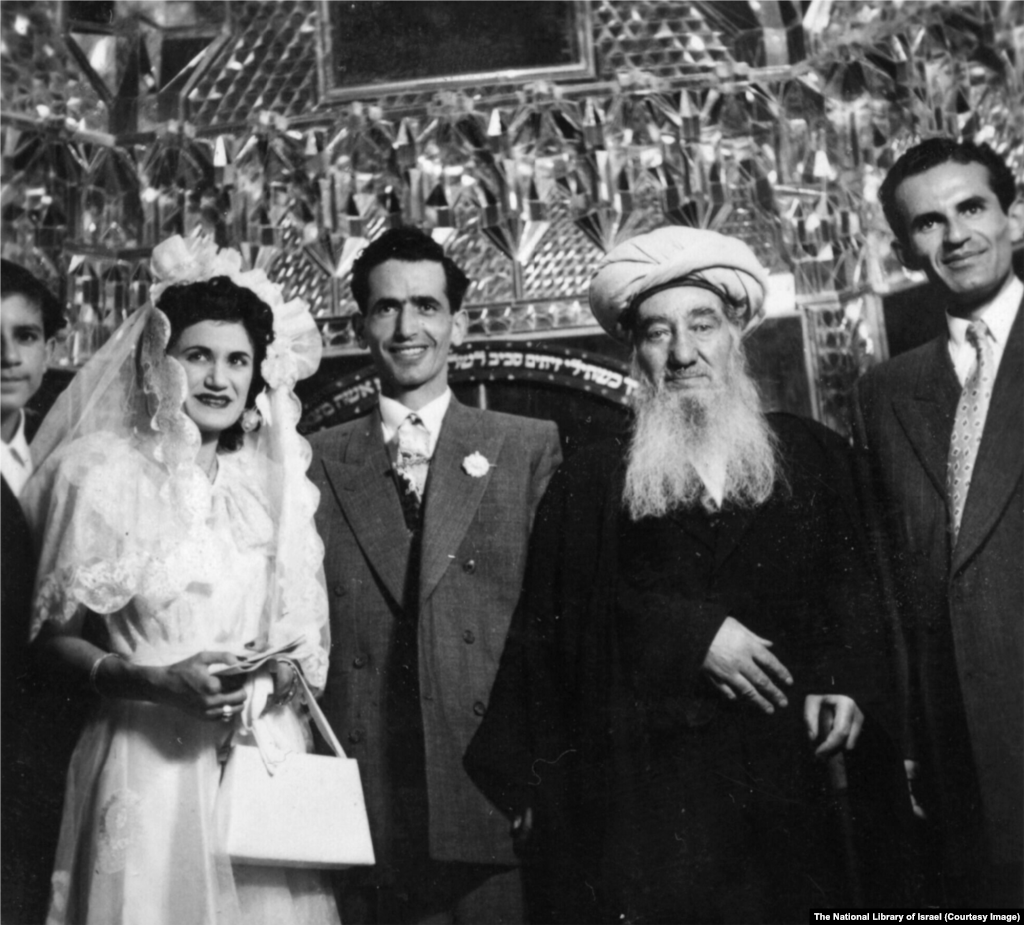Єврейське весілля у невстановленому місці в Ірані в 1950-х роках. Церемонію проводить головний рабин країни Шломо Коен Цедек (в центрі праворуч).Позаду людей видно фрагмент біблійного вірша на івриті: «Твоя дружина буде як виноградна лоза в твоєму домі; твої діти будуть як оливкові пагони навколо твого столу»