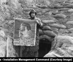 Корейская война 1950-53 годов: американский солдат позирует с портретом Сталина, найденным на захваченных позициях северокорейских войск и их китайских союзников