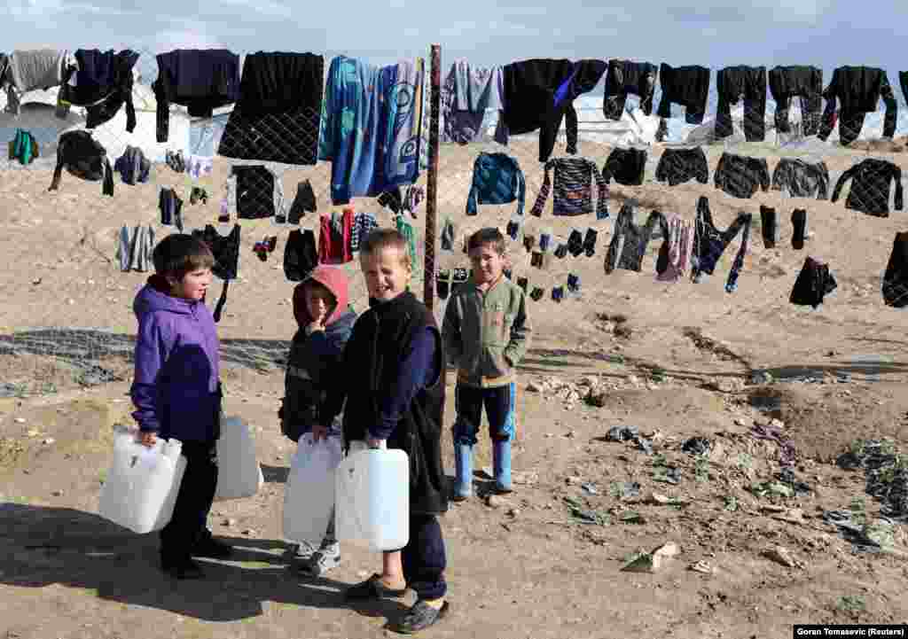 Children hold water containers in the al-Hol camp.