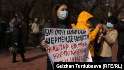 Одна из акций «За солидарность» в Бишкеке. Участница акции держит плакат с призывом против коррупции. 