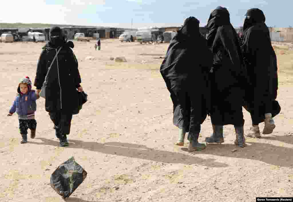 A woman holds hands with a child while walking through al-Hol refugee camp in Syria.&nbsp;