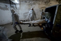 Pathologists in protective suits transport the body of a person who died of COVID-19 at a hospital morgue in Bishkek.
