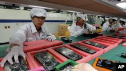 Китайські працівники заводу Foxconn збирають американські смартфони iPhone компанії Apple. 26 травня, 2010 року