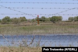 Тікенек сымның ар жағында тұрған Ресей федерациясының шекара бағаны. Көптоғай ауылы, Атырау облысы. 4 мамыр 2021 жыл.
