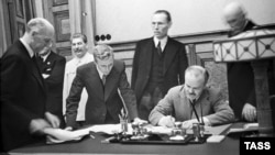 Міністр закордонних справ СРСР В'ячеслав Молотов (праворуч, сидить) підписує пакт Молотова-Ріббентропа. Третій ліворуч – генеральний секретар ЦК ВКП(б) Йосип Сталін. Москва, 23 серпня 1939 року