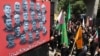 Mourners walk by a poster bearing the portraits of scientists and military commanders killed during the 12-day war between Iran and Israel, in Tehran on July 5.