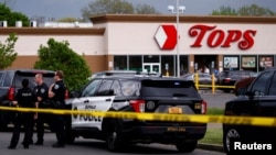Полициски службеници го обезбедуваат местото на настанот по пукањето во супермаркетот ТОПС во Бафало. 