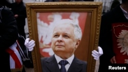 Мъж държи снимка на покойния полски президент Лех Качински по време на възпоменателна церемония за самолетната катастрофа през 2010 г. пред президентския дворец във Варшава. 10 февруари 2016 г.