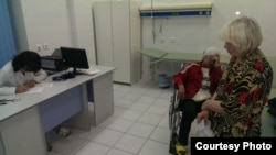 Участница акции протеста в форме «сухой​ голодовки» Батима Берсанова (в инвалидном кресле) в больнице. Рядом стоит представитель участников акции протеста Ольга Рубахова. Астана, 23 августа 2014 года. Фото предоставлено родственниками Батимы Берсановой.    
