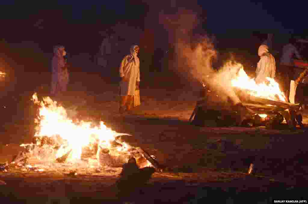 Членови на едно семејство над телата на нивните најблиски за време на кремирање на северот на земјата, во Алахабад, Утар Прадеш, на 6 мај 2021 година.