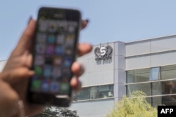 NSO group компаниясы ғимараты маңында iPhone смартфонын көрсетіп тұрған адам. Израиль, 28 тамыз, 2016 жыл.