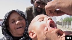 A Pakistani health worker orally administers a polio vaccination to a child.