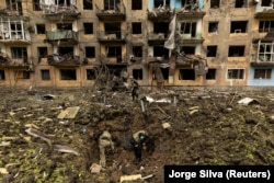 Украінскія вайскоўцы аглядаюць месца ракетнага ўдару каля жылога дома ва ўкраінскім Дабрапольлі Данецкай вобласьці, 30 красавіка 2022 года