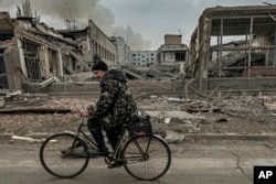 Чоловік їде на велосипеді повз поштове відділення, знищене внаслідок російського авіаудару в Кураховому, Донецька область, Україна, 7 листопада 2024 року