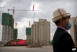 A man stands on a plaza near a display with the Chinese flag at the Xinjiang Islamic Institute in western China.