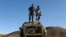 FILE: Two Afghan policemen keep watch atop the remains of a Soviet-era armored personnel carrier at Islam Qala border crossing with Iran in the western province of Iran.