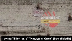 A banner reading "Save Us" hangs from a brick prison wall.