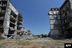 Чоловік між зруйнованими будівлями в Ізюмі Харківської області, 27 липня 2023 року