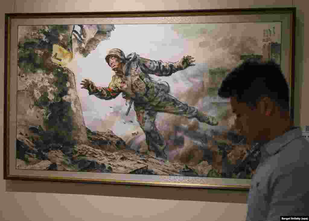 Полотно под названием «Отдаю бесценную жизнь» на выставке северокорейского искусства в Москве 8 октября.Эта картина — одна из нескольких на выставке, на которых изображены северокорейские солдаты, участвовавших в войне против украинских войск в войне Москвы против Киева