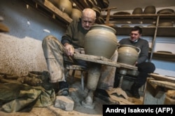 Goran Savic (right) and his 91-year-old grandfather, Milan, shape clay cooking pots in the village of Zlakusa, in central Serbia, on December 28.