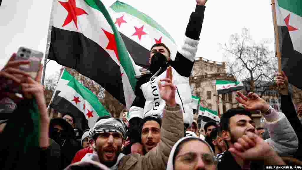  Pristalice sirijske opozicije mašu zastavom sirijske opozicije, poznatom i kao zastava revolucije, i uzvikuju slogane tokom skupa koji je sazvala grupa Kampanja sirijske solidarnosti na Trafalgar skveru, u centru Londona. Zamenica britanskog premijera Angela Rejner pozvala je na &quot;političko rešenje&quot; u Siriji. &nbsp; 