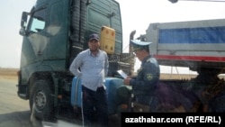 Polisiýanyň ýol gözegçisi sürüjiniň dokumentlerini barlaýar. Tejen, aprel, 2018.