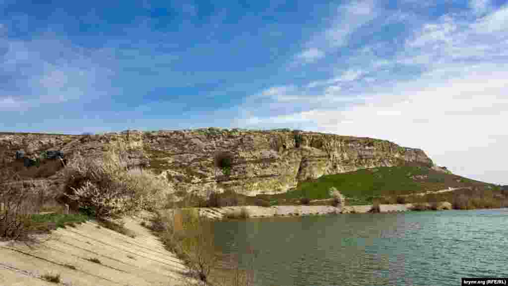 Вид на Волчий грот (слева от цветущей алычи) с дамбы водохранилища на реке Бештерек