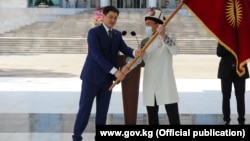 Председатель кабмина Улукбек Марипов вручает флаг Кыргызстана капитану олимпийской сборной Атабеку Азисбекову. 13 июля 2021 года.