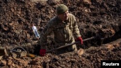 Un militar ucrainean sapă un șanț în afara orașului Bahmut, în Donețk, pe 4 martie 2023. 