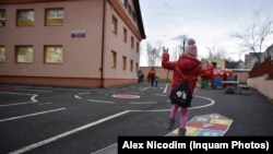 Un copil se joacă la sosirea la școală.